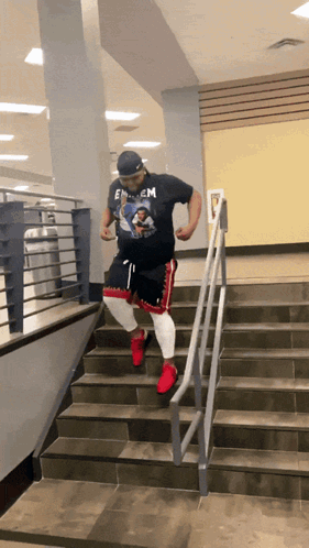 A Man Wearing A Shirt That Says Eminem Is Walking Down Stairs GIF