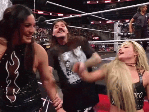 A Man Wearing A Shirt That Says ' G ' On It Is Laughing With Two Women In A Wrestling Ring GIF