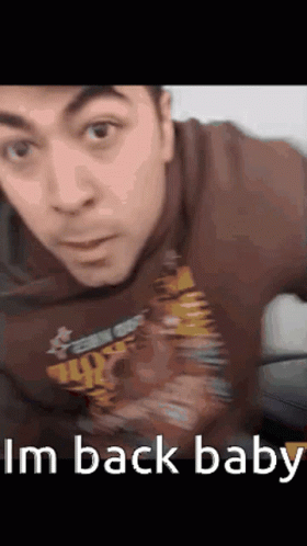 A Man Wearing A Shirt That Says I 'M Back Baby Looks At The Camera GIF