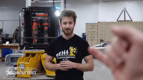 A Man Wearing A Shirt That Says Jacksmith Industries Stands In A Factory GIF