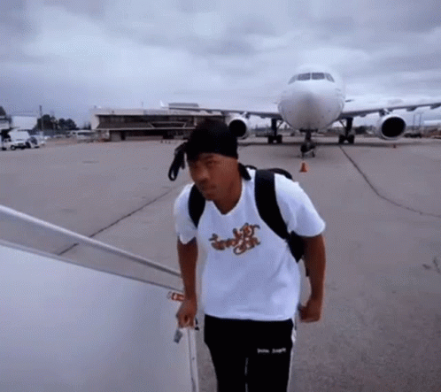 a man wearing a shirt that says ' jungle ' on it is walking towards an airplane