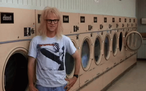 A Man Wearing A Shirt That Says Led Zeppelin Is Leaning Against A Washing Machine GIF