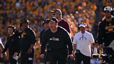 A Man Wearing A Shirt That Says Son Of Evil Stands On A Football Field GIF