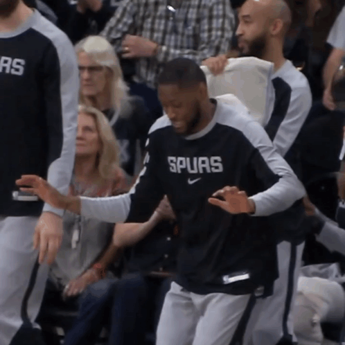 A Man Wearing A Shirt That Says Spurs Is Being Helped By Another Man GIF