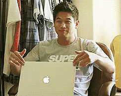 A Man Wearing A Shirt That Says Super Is Sitting In Front Of A Laptop GIF