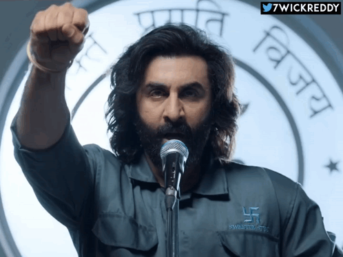 A Man Wearing A Shirt That Says Swastik Trust GIF