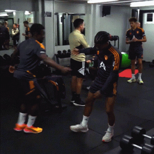 A Man Wearing A Shirt With The Letter A On It Stands In A Gym GIF