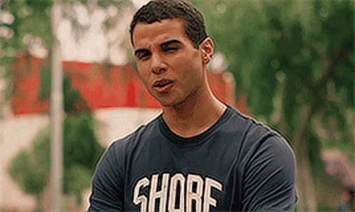 A Man Wearing A Shore T-Shirt Is Standing In Front Of Trees . GIF