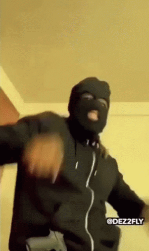 A Man Wearing A Ski Mask And Holding A Gun Is Dancing . GIF