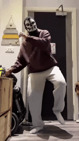 a man wearing a skull mask is dancing in a room