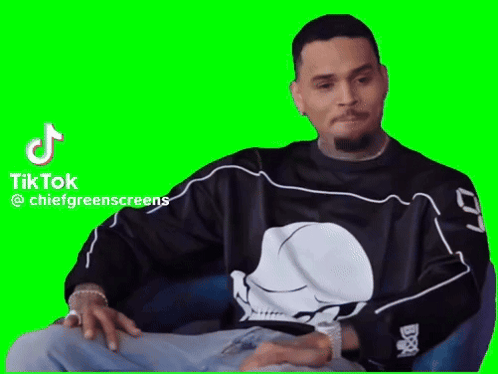 A Man Wearing A Skull Shirt Is Sitting In A Chair With His Hands On His Knees . GIF