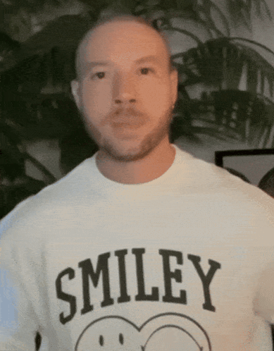A Man Wearing A Smiley T-Shirt With A Smiley Face On It GIF