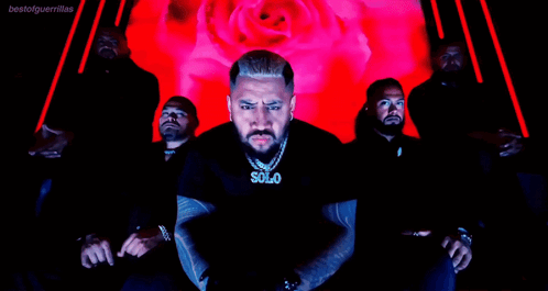 A Man Wearing A Solo Necklace Stands In Front Of A Group Of Men GIF