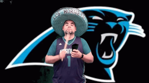 A Man Wearing A Sombrero And A Hornets Jersey Holds A Phone In Front Of A Panthers Logo GIF