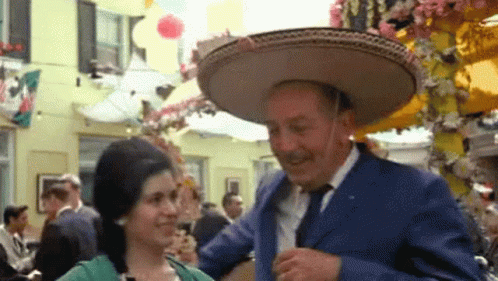 A Man Wearing A Sombrero Is Dancing With A Woman In A Green Dress GIF