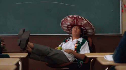 A Man Wearing A Sombrero Sits In A Chair In Front Of A Chalkboard GIF