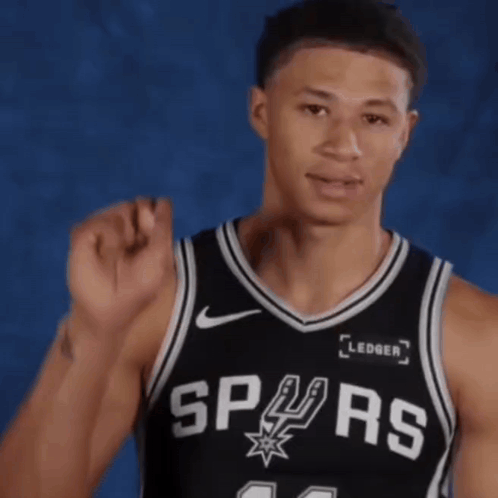 A Man Wearing A Spurs Jersey Holds His Fist Up In The Air GIF