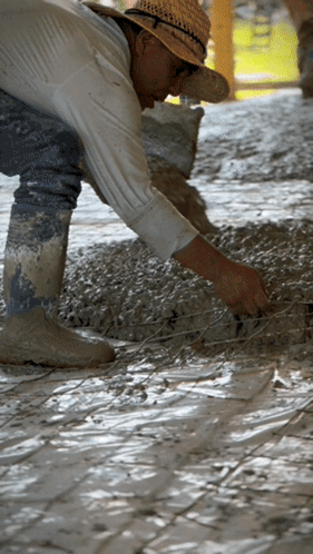 A Man Wearing A Straw Hat Is Working On A Tile Floor GIF