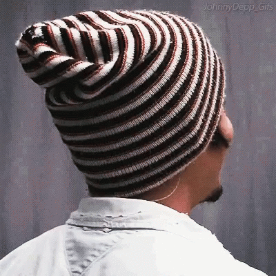 A Man Wearing A Striped Beanie Is Looking To The Side GIF