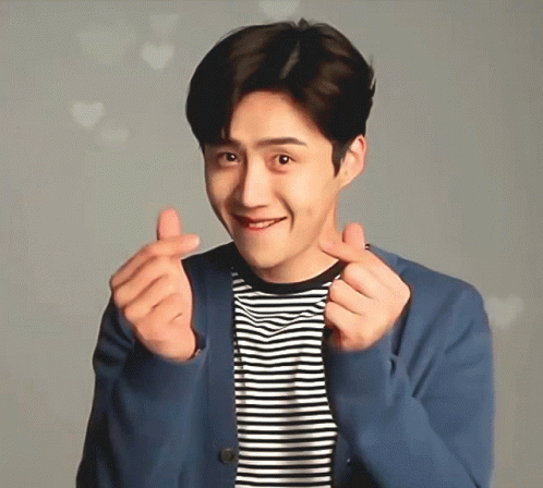 A Man Wearing A Striped Shirt And A Blue Jacket Is Making A Heart With His Hands GIF