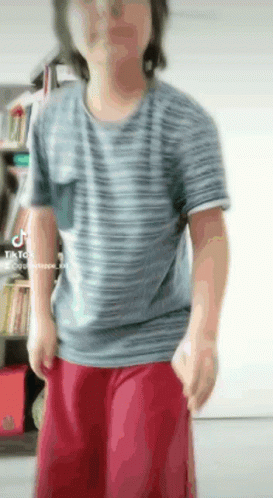 a man wearing a striped shirt and red shorts is standing in a room .