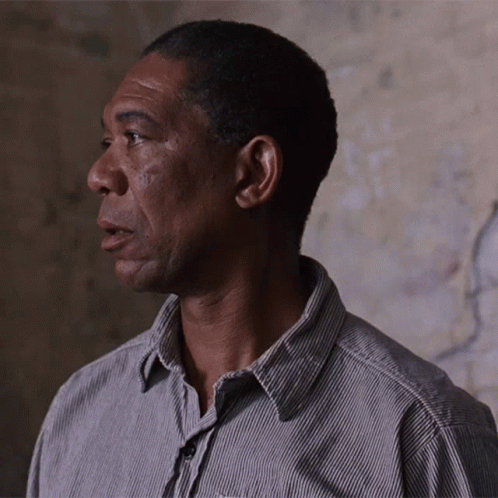 A Man Wearing A Striped Shirt Looks To His Left GIF