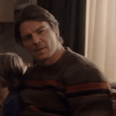A Man Wearing A Striped Sweater Is Looking At Something GIF