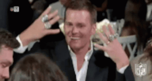 A Man Wearing A Suit And A White Shirt Is Surrounded By People With Their Hands In The Air . GIF