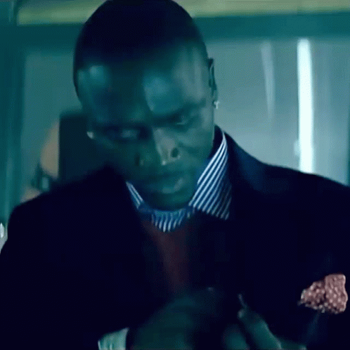 A Man Wearing A Suit And Striped Shirt Is Looking Down GIF
