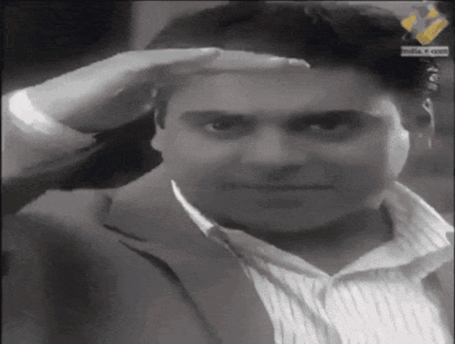 A Man Wearing A Suit And Striped Shirt Salutes With His Hand On His Forehead GIF