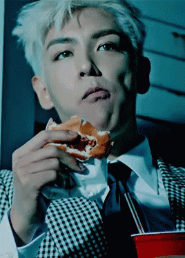 A Man Wearing A Suit And Tie Is Eating A Hamburger GIF