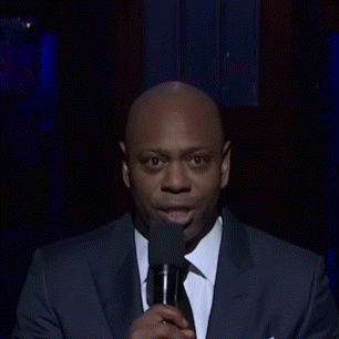 A Man Wearing A Suit And Tie Is Making A Funny Face GIF