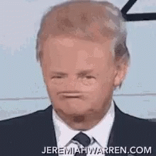 A Man Wearing A Suit And Tie Is Making A Funny Face . GIF