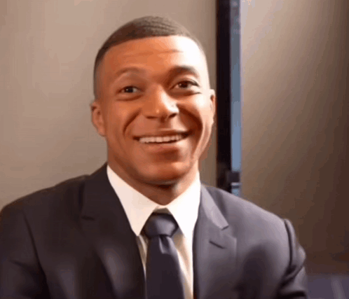 A Man Wearing A Suit And Tie Is Smiling GIF
