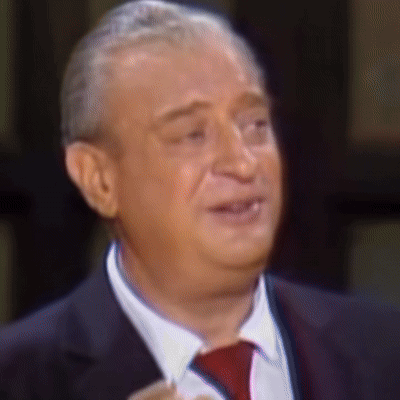 A Man Wearing A Suit And Tie Is Smiling GIF