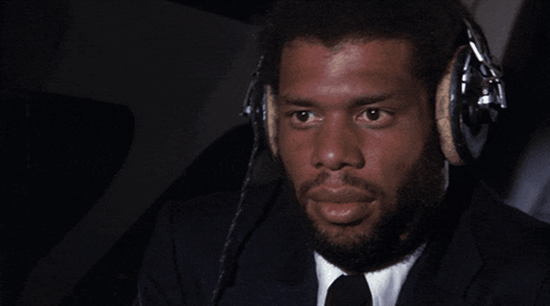 A Man Wearing A Suit And Tie Is Wearing Headphones GIF