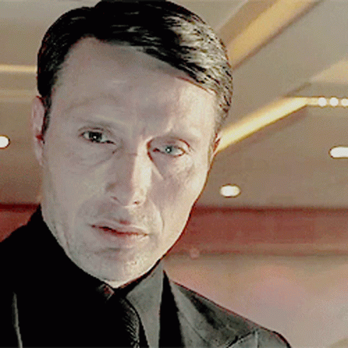 A Man Wearing A Suit And Tie Looks At The Camera GIF