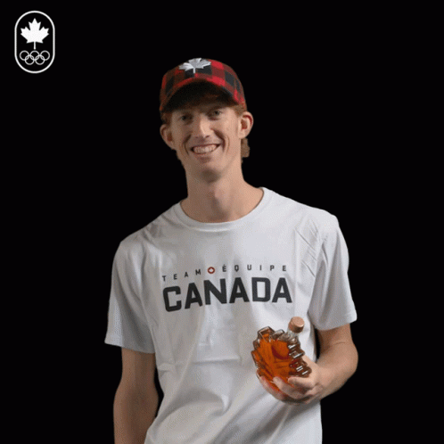 a man wearing a t-shirt that says canada drinks from a bottle