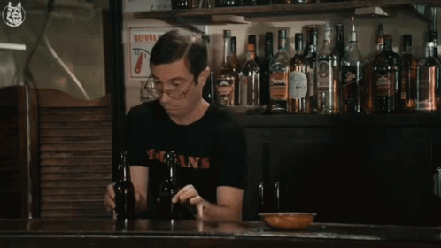 A Man Wearing A T-Shirt That Says Dsans Holds A Bottle GIF