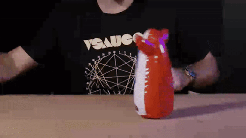 A Man Wearing A T-Shirt That Says " Sauce " Is Holding A Red And White Inflatable Animal GIF