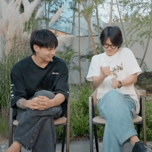A Man Wearing A T-Shirt That Says Tears Sits Next To Another Man In A Chair GIF