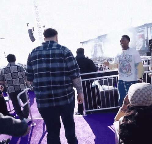A Man Wearing A T-Shirt With A Dog On It Stands In A Crowd Of People GIF