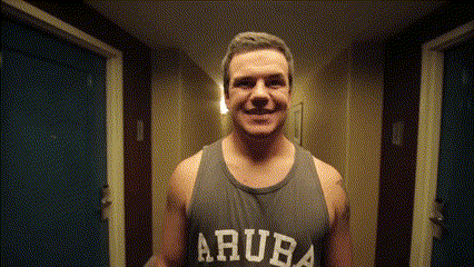 A Man Wearing A Tank Top That Says Aruba Smiles In A Hallway GIF