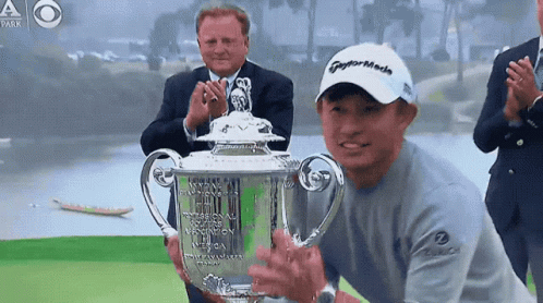 A Man Wearing A Taylormade Hat Holds Up A Trophy GIF