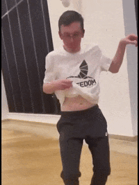 A Man Wearing A Tedom Shirt Is Dancing In A Dance Studio GIF