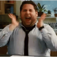 A Man Wearing A Tie And A Blue Shirt Is Making A Funny Face . GIF