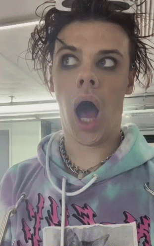 A Man Wearing A Tie Dye Hoodie With A Cat On It Makes A Funny Face GIF