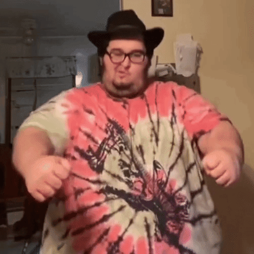 A Man Wearing A Tie Dye Shirt And A Cowboy Hat Is Dancing GIF