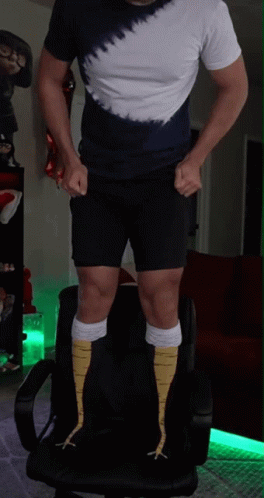 A Man Wearing A Tie Dye Shirt And Shorts Is Standing On A Chair GIF