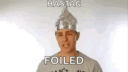 A Man Wearing A Tin Foil Hat And A T-Shirt Is Making A Funny Face . GIF